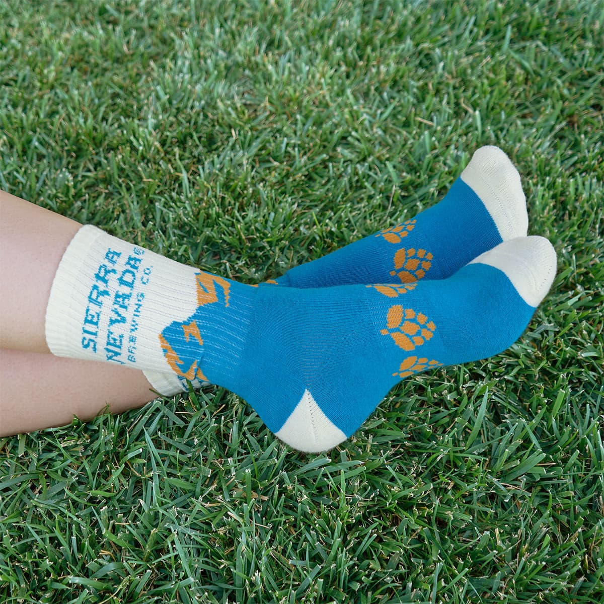 A person wears the Sierra Nevada Blue Mountain Socks outside in a grassy field