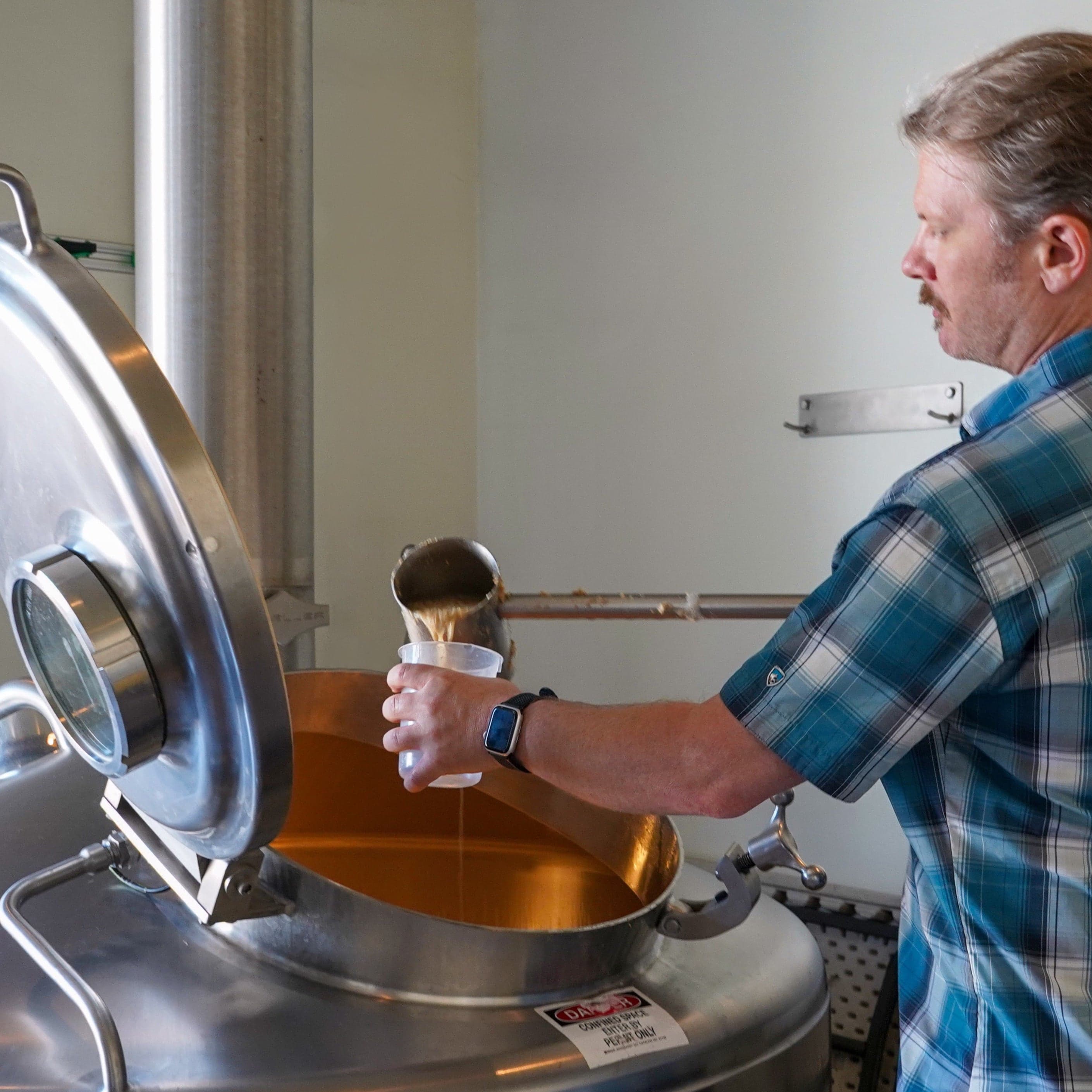 A brewer tests the liquid during the brewing process for the CCBA West Coast IPA from Sierra Nevada.