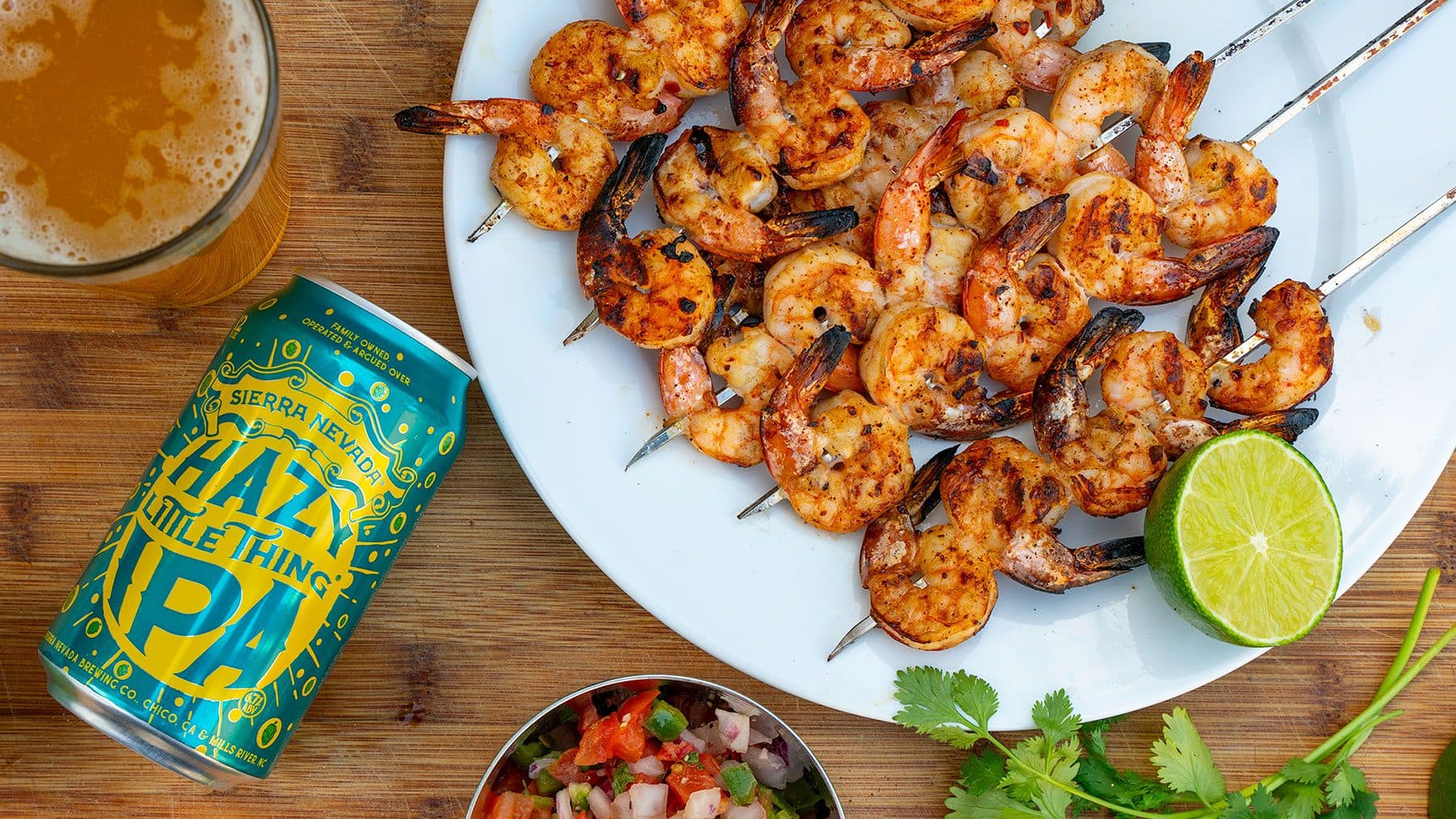 A can of Hazy Little Thing next to grilled shrimp skewers